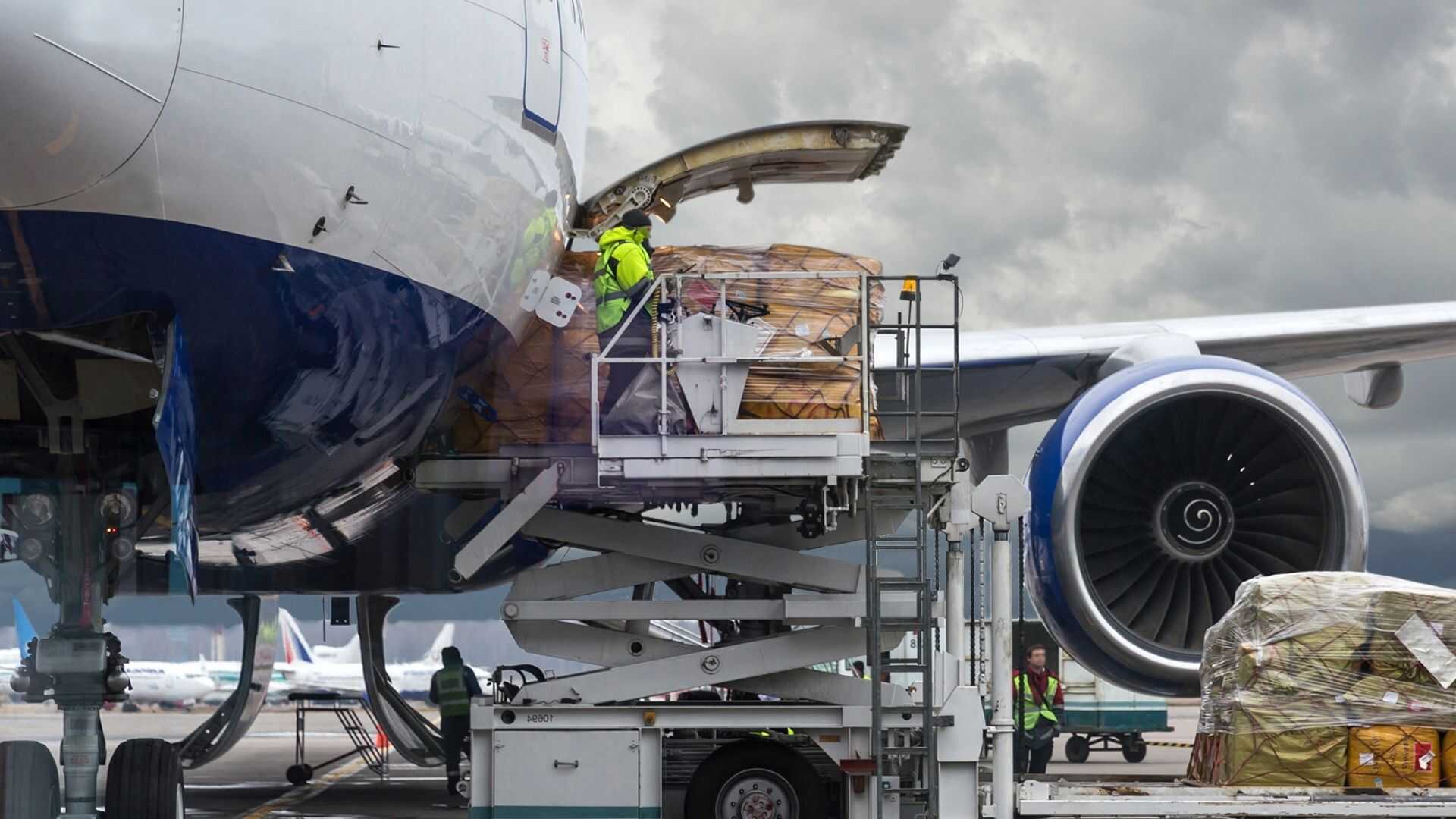 Ground operations specialist on a high-loader platform loading heavy freight into a chartered freighter aircraft.